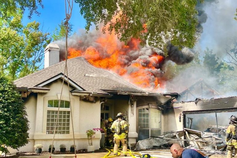 Brandweermensen aanpakken een vuur dat een huis in vlammen zet.